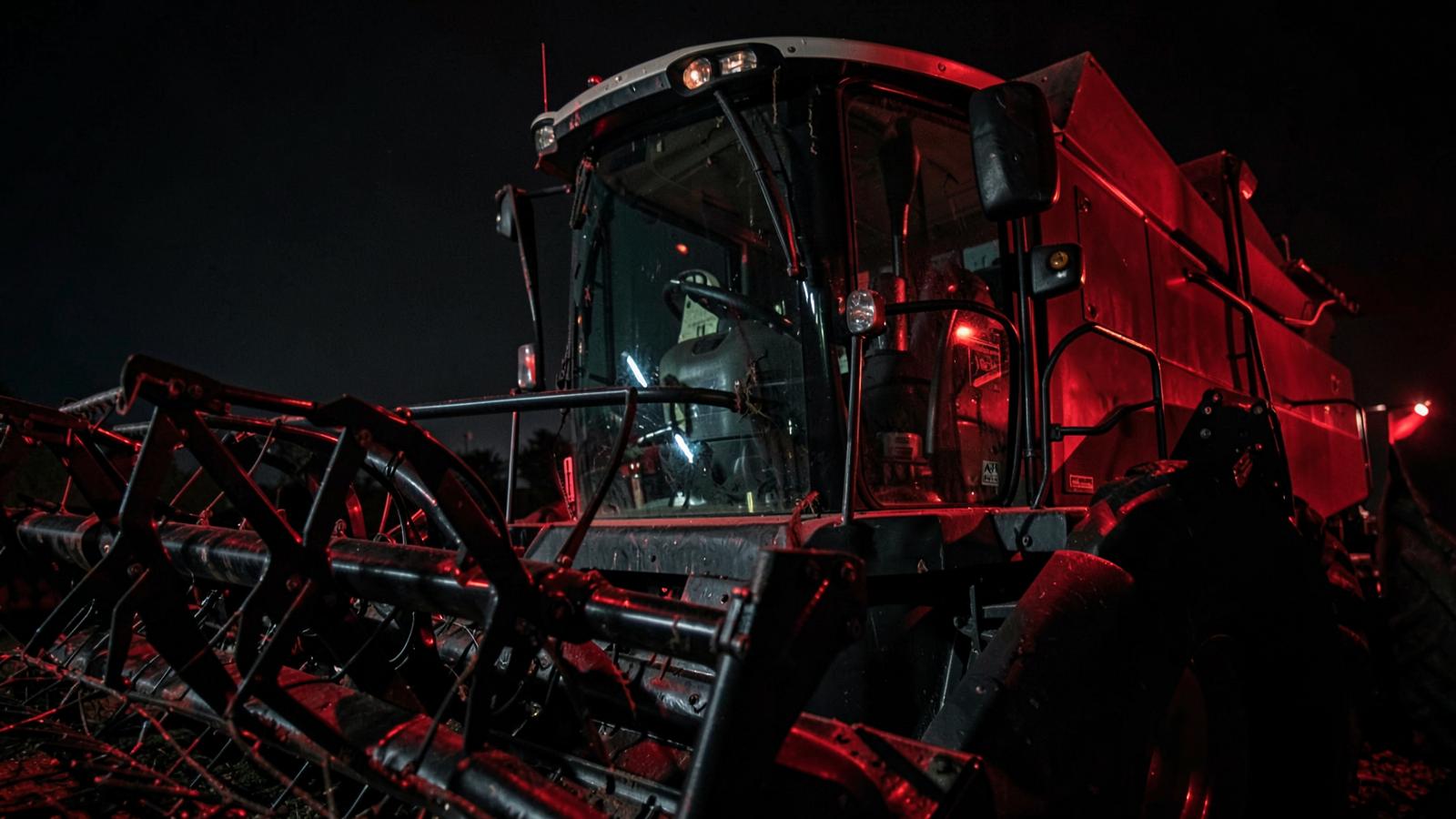 Colheitadeira agrícola iluminada em vermelho durante a noite